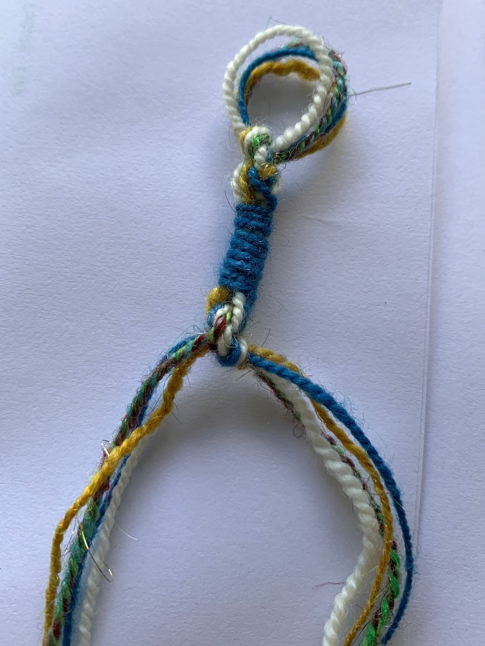 a sample loop of tzitzit string with white, gold, blue, and rainbow threads.