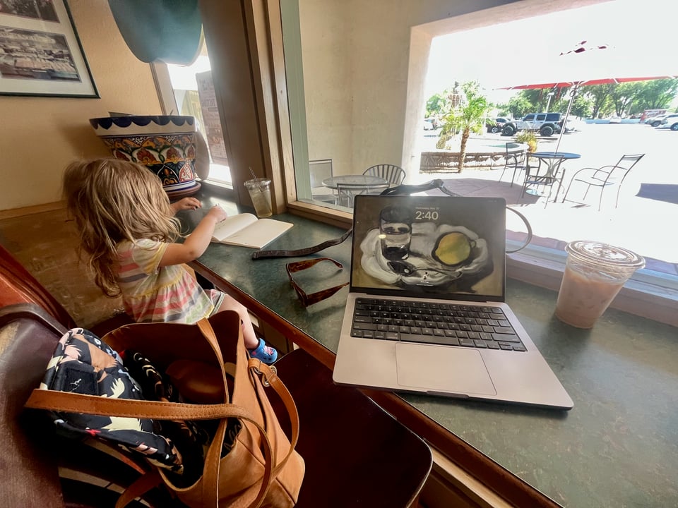 a bar height table at the coffee shop, with my laptop open and daughter drawing