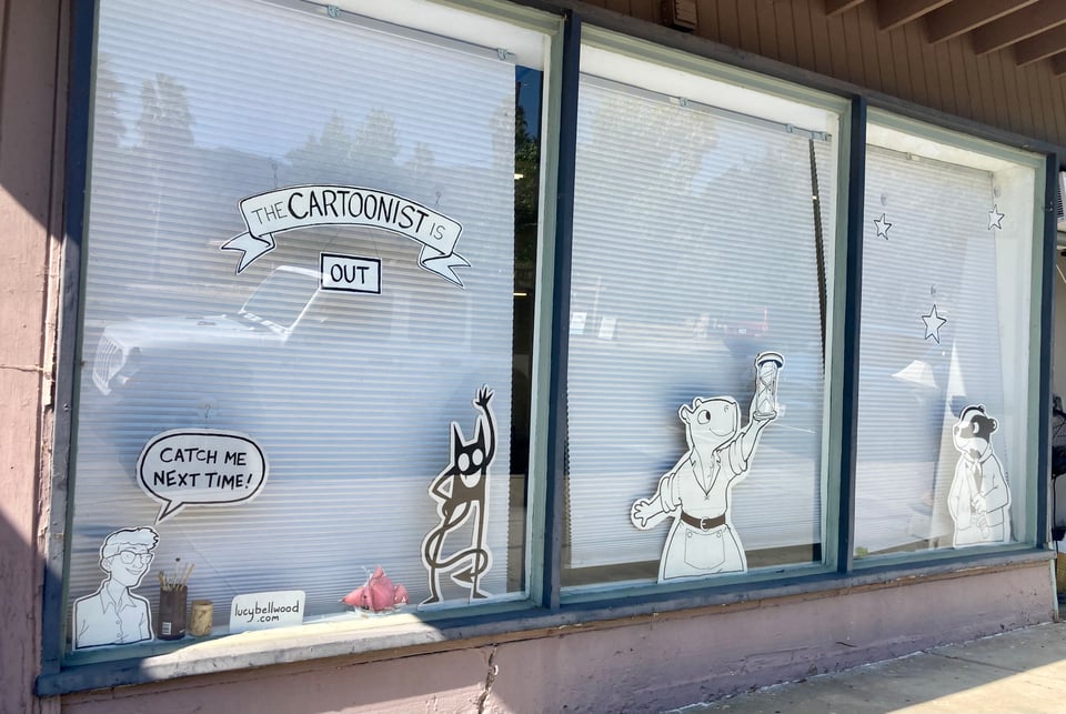 The windows of Lucy's studio, complete with cardboard cutouts of her characters and a sign saying