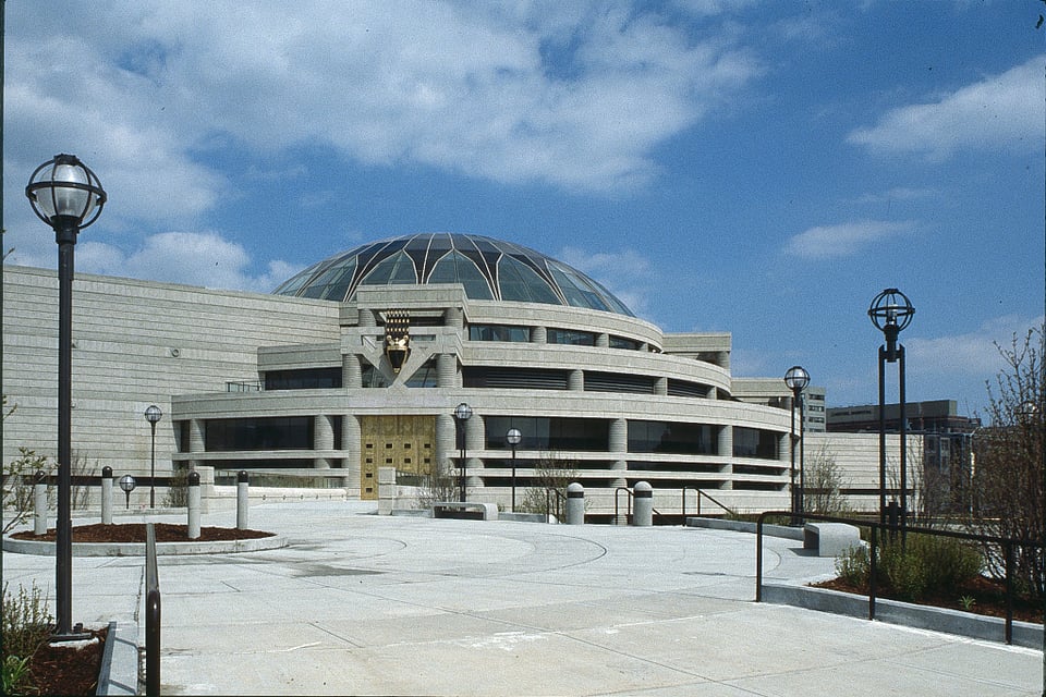 A photo of a building with a dome under a blue sky with some clouds.