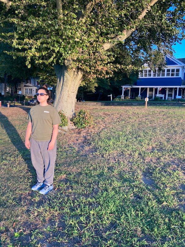 Photo of Nicole in front of a tree and a blue house facing the Delaware River