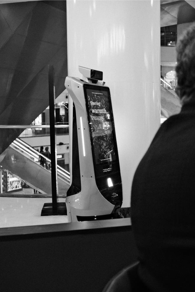 Robot at the Mall with a screen that says "Sharing warmth spreading joy