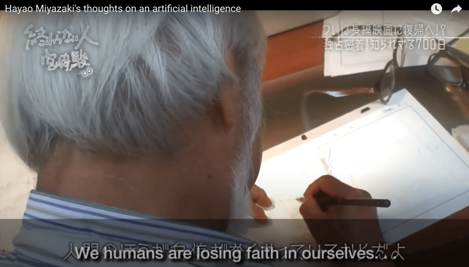 Hayao Miyazaki is drawing on a lightpad and the camera is behind him. He's saying: 'We humans are losing faith in ourselves.'