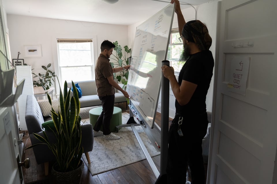 Two people moving a whiteboard.