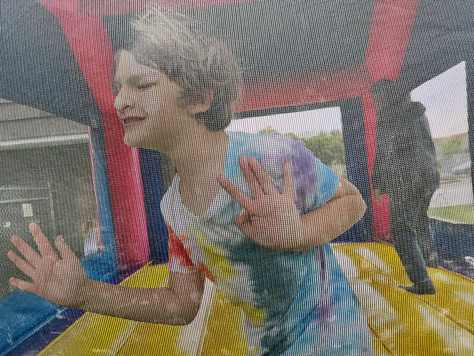 An elementary aged kid in total ecstasy playing in a bounce house.