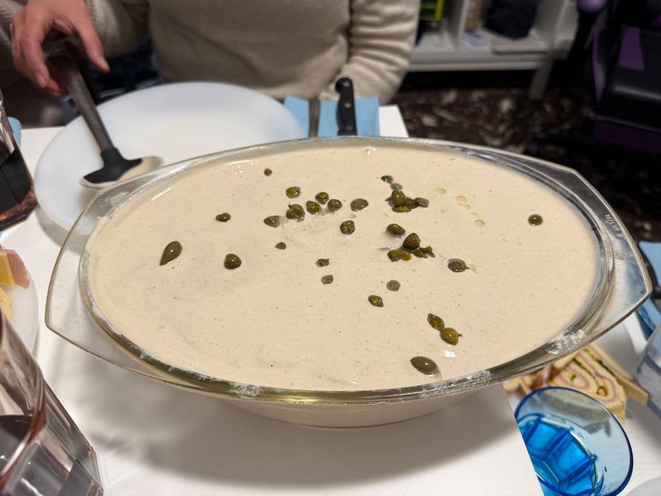 A bowl of 'vitel tone' is filled to the brim with cream sauce. Capers are on the top.