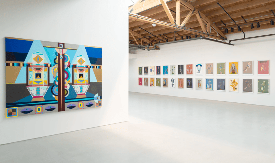 a white-walled gallery with many abstract paintings hung on the walls