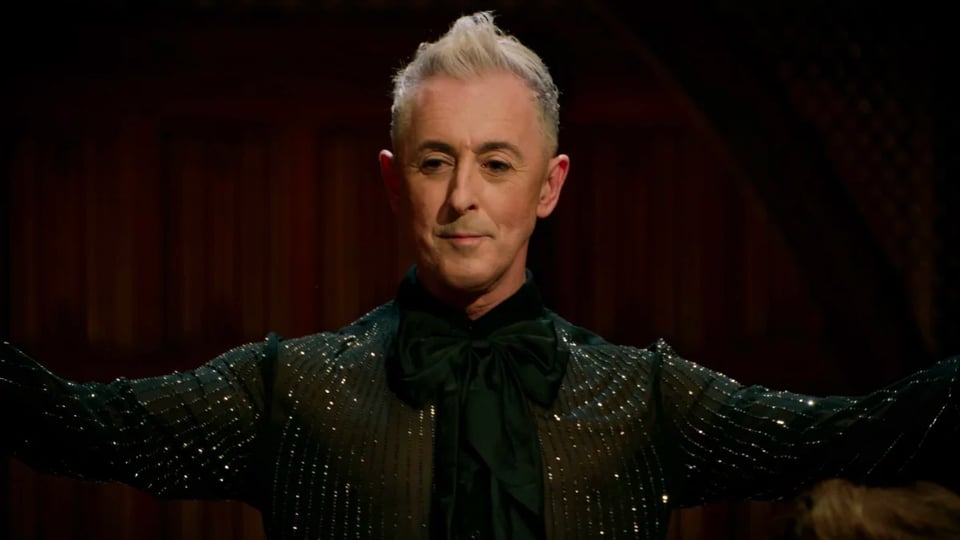 A man in a sparkly black suit with his arms outstretched