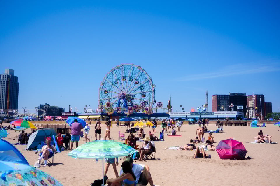 Beachgoers scattered across the sand with the Wonder Wheel in the background,