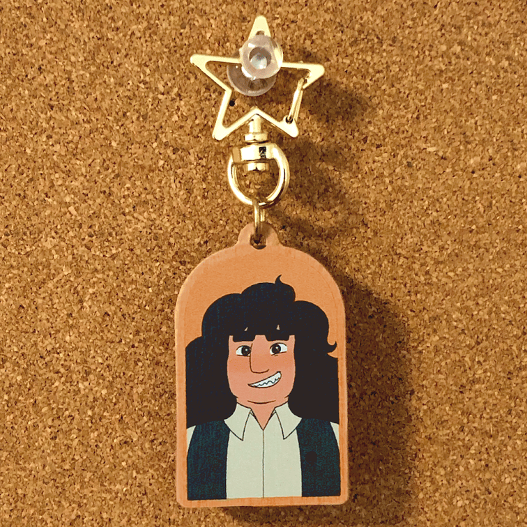 A photo of Jane from Runaway Drakaina on an arch shaped wooden keychain with a star shaped clasp.