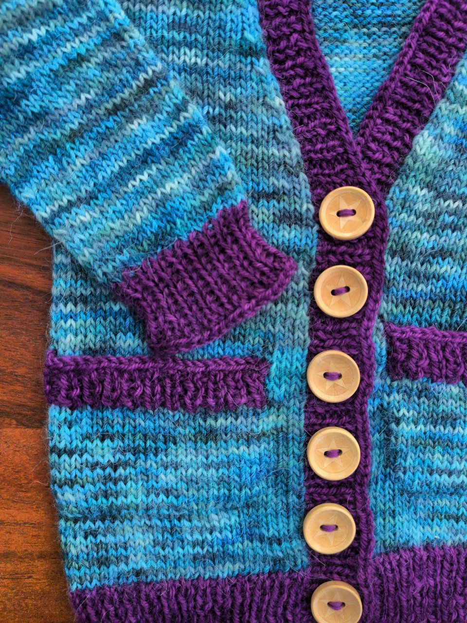 a closeup on the cardigan from the previous photo showing the soft texture of the yarn and the little stars laser cut onto the round wooden buttons.
