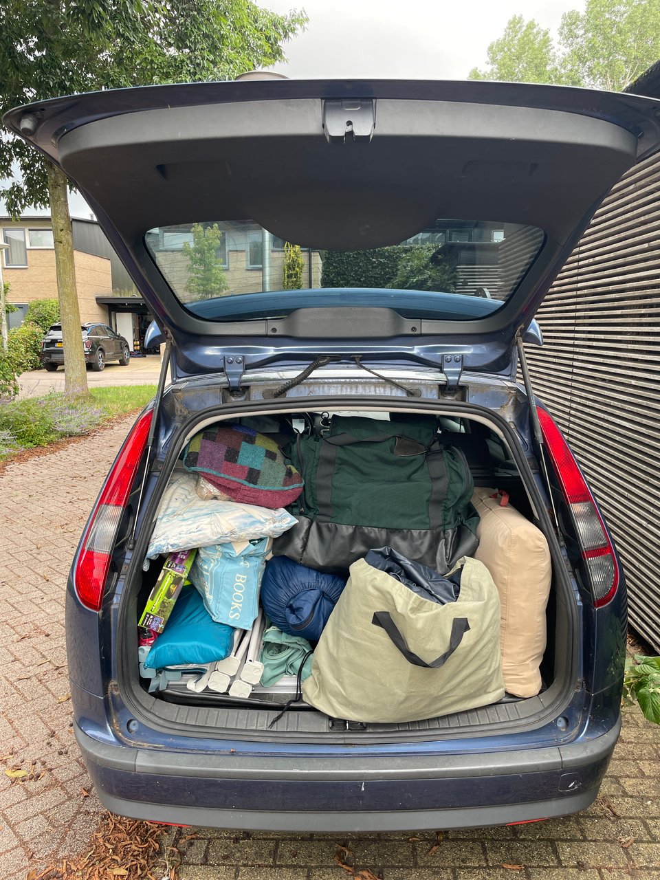 Station wagon trunk open and the back is completely full of a family's belongings for a camping trip.