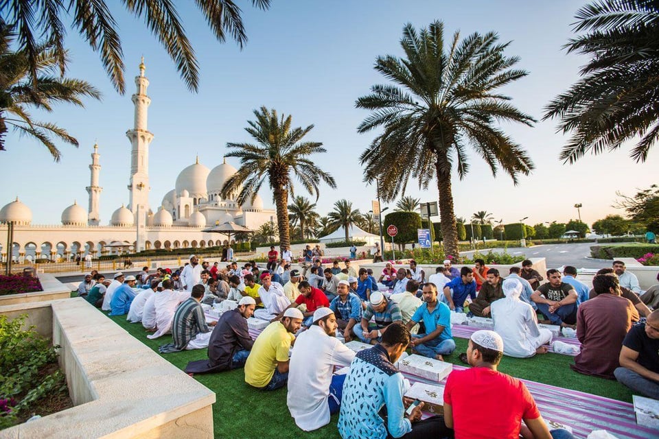 People gathered outside the grand mosque seated on the ground for a meal