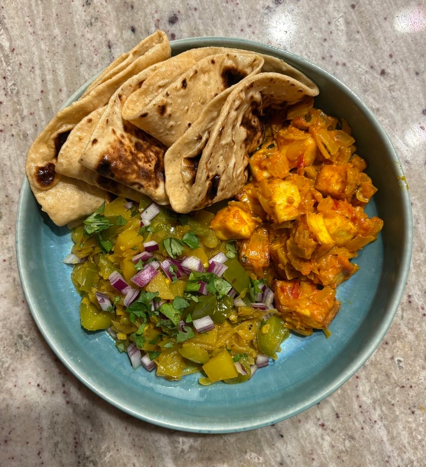 A blue plate loaded with shimla mirch sabzi, roti, and saloon paneer.