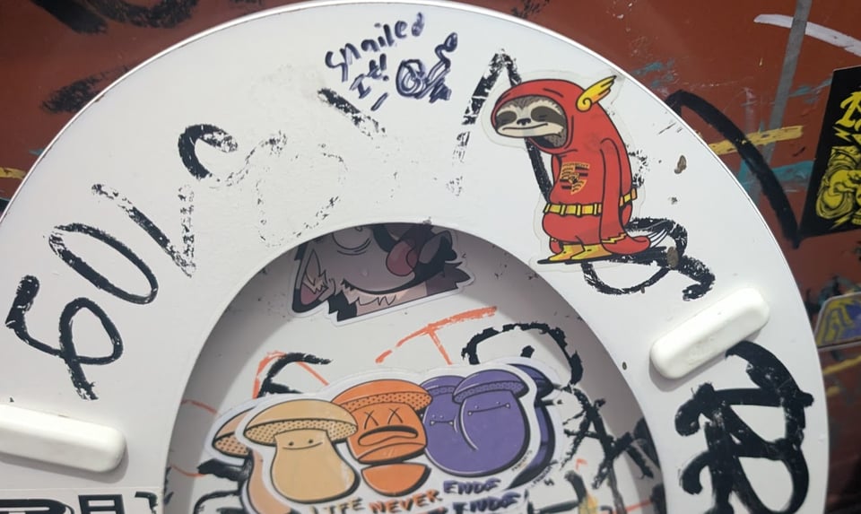 It's a toilet seat flipped upwards to reveal a sticker showing a sloth dressed as the Flash, the fastest man alive. The sloth looks extremely chill and not fast.