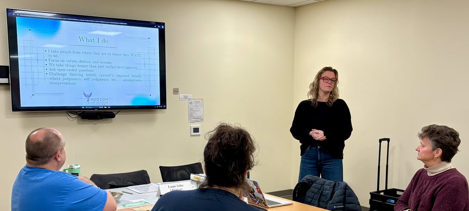 Krista explains to NRG members the services she provides, with the aid of a presentation slide on the wall-mounted screen.
