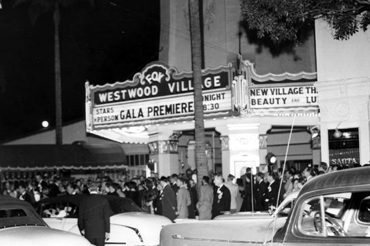 Vintage movie theater marquis with the words Gala Premiere. Large crowd and traffic out front.