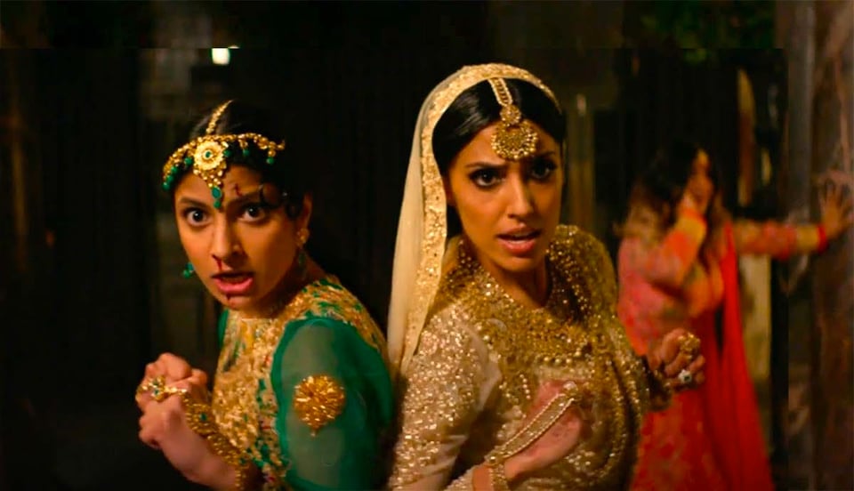 An image from the movie Polite Society, showing Ritu Arya as Lena and Priya Kansara as Ria, in a fight scene while wearing beaitful wedding outfits