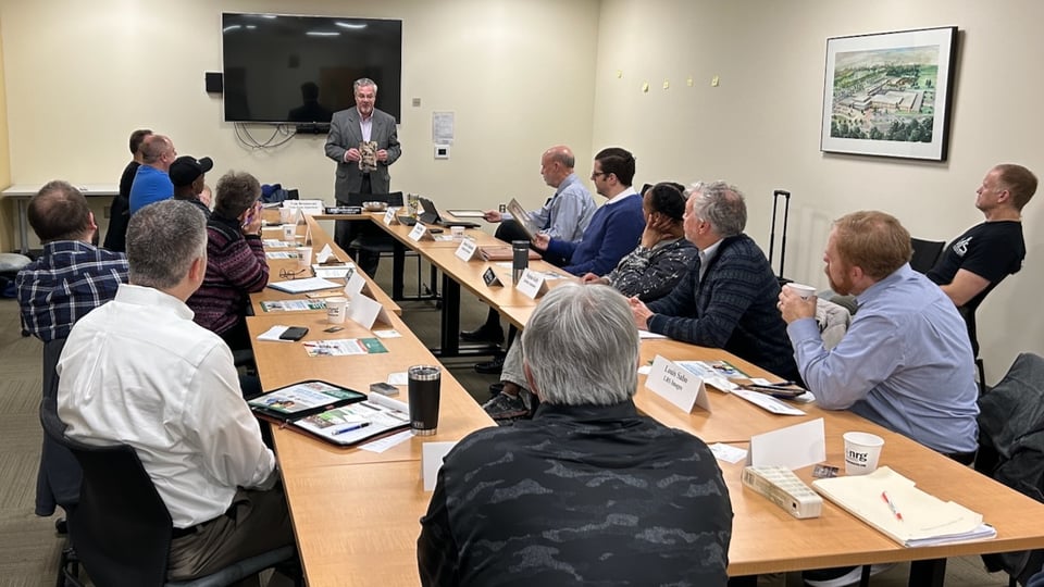 Darryl Powell is holding up one of his customer’s books he helped publish in front of the NRG group.