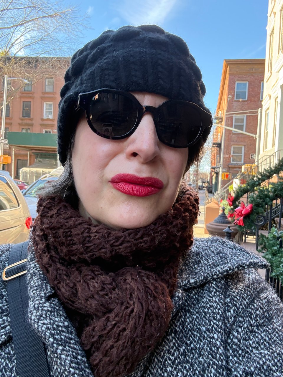 Amanda Schuster wearing winter gear and bright red Negroni lipstick by GIELLA walking in the sunshine in Cobble Hill, Brooklyn