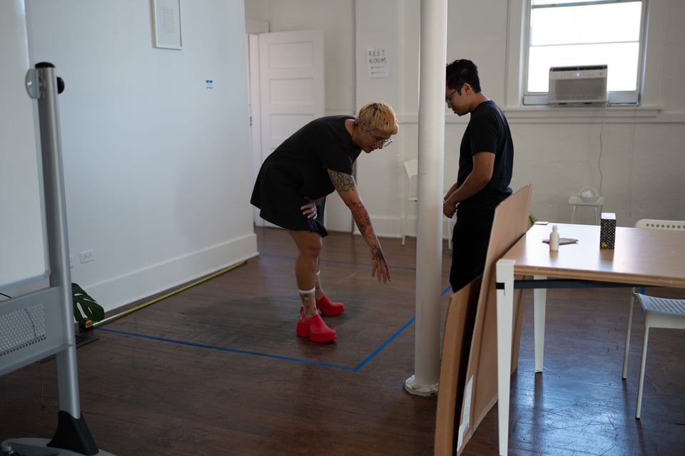 Beth and Norton taping a space on the ground.