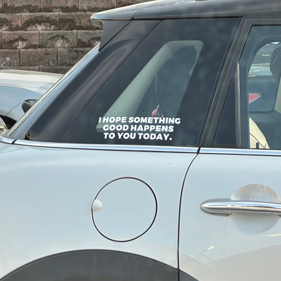 Photo of a Mini Cooper with a decal in the right-side trunk-window, reading, "I HOPE SOMETHING GOOD HAPPENS TO YOU TODAY"