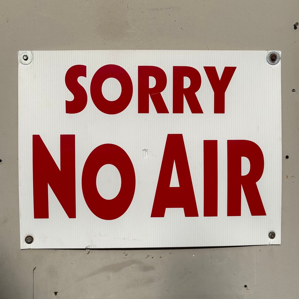 photo of gas station sign that reads, "SORRY NO AIR" in red letters on white background