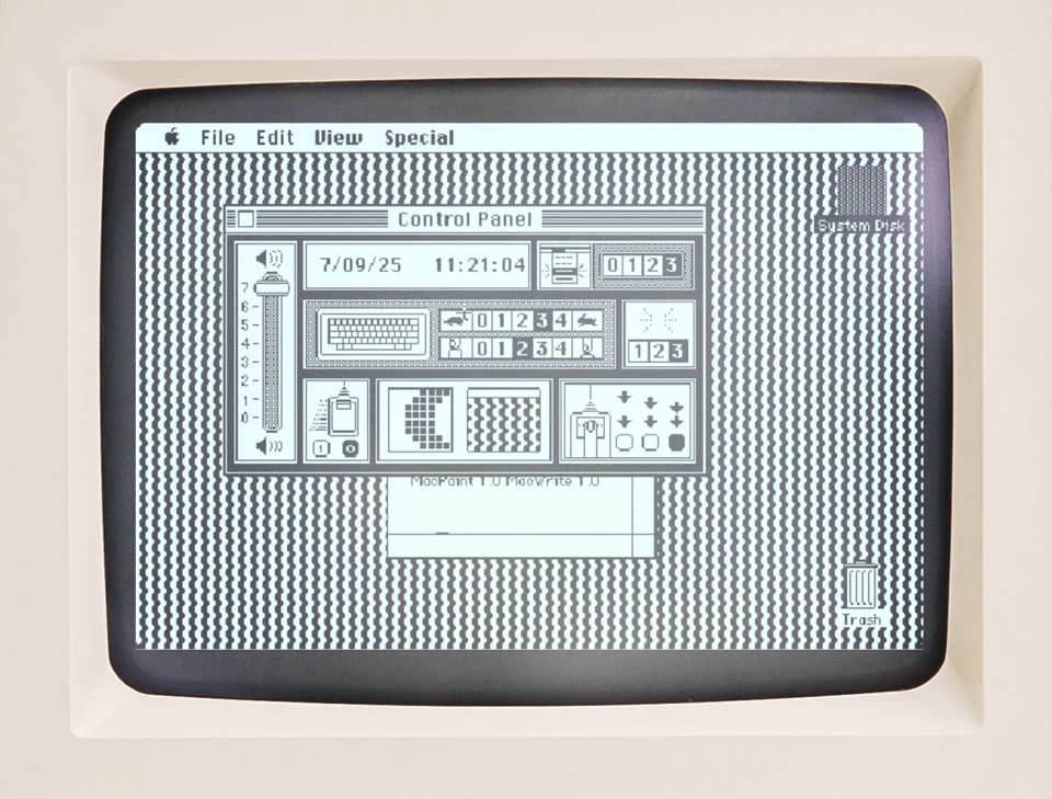 A 1984 Macintosh displaying its classic black-and-white graphical user interface, with the control panel open. The panel features sliders, icons, and time/date settings -- you can move a slider to raise or lower the volume, type in the correct time and date, click four possible speeds for the keyboard (with "slow" represented by a tiny icon of turtle, and "fast" by an icon of a hare), select three possible speeds for the double-click on a mouse, and pick an 8X8 pattern for the background image. The author has used this background feature to create a C-shape that is tiled on the background, creating scalloped lines that go up and down