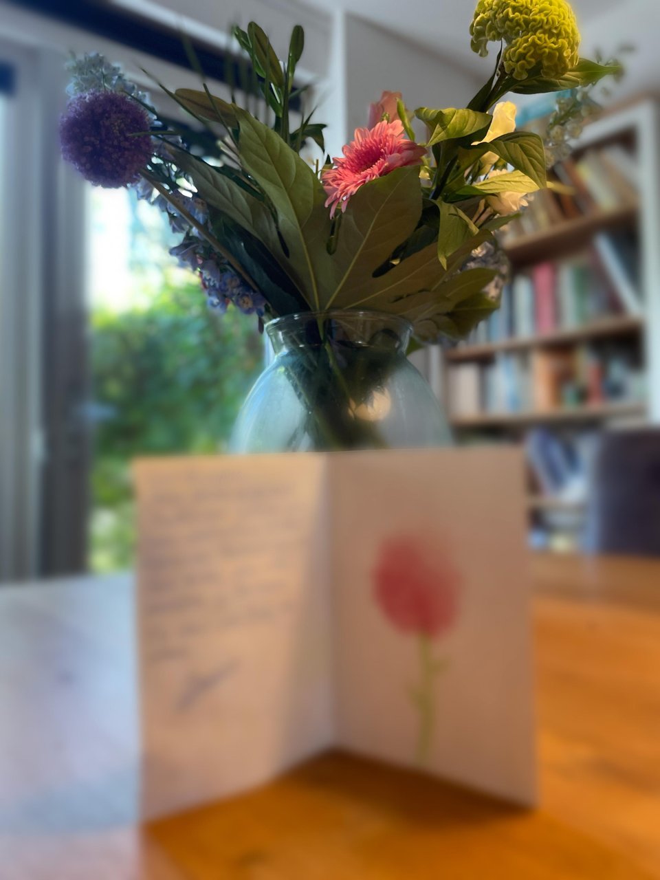 An anniversary card is blurred out and a large vase of flowers is in the background.