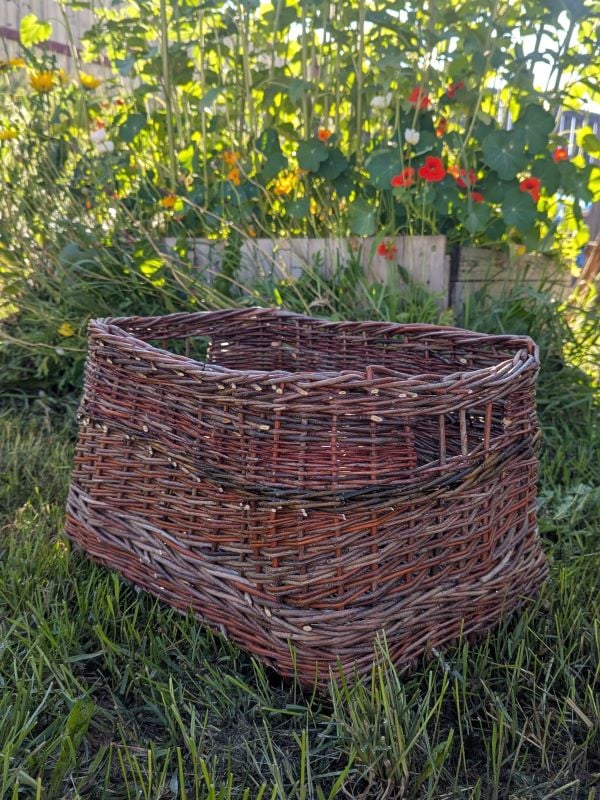 Rectangle woven willow basket in the grass with flowers in the background