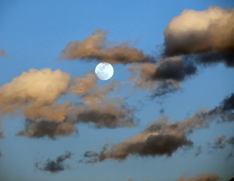 a full moon partially behind clouds
