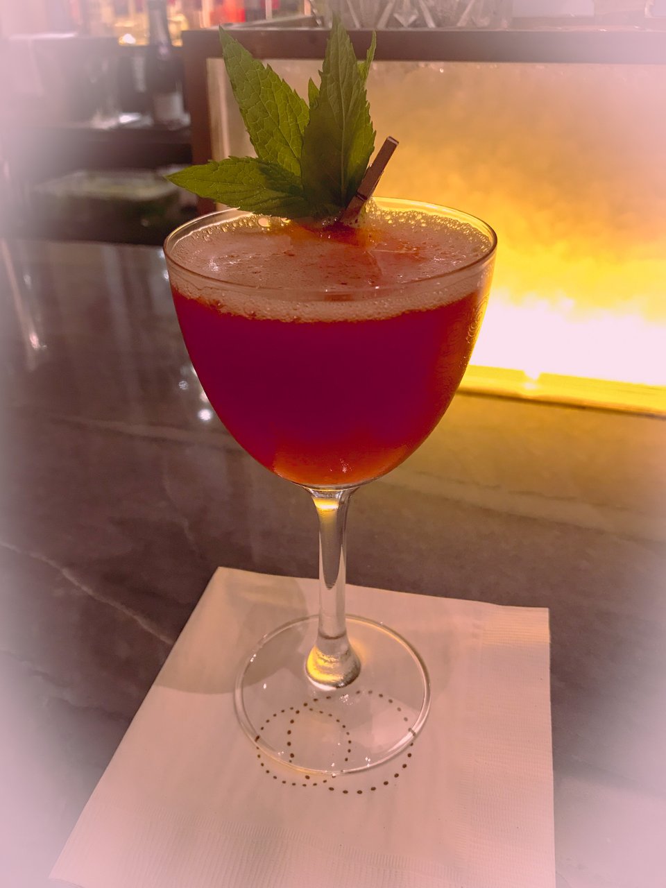 Bright red strawberry cocktail — Meet El Presidente — served on a napkin at the bar at Restaurant Daniel, NYC