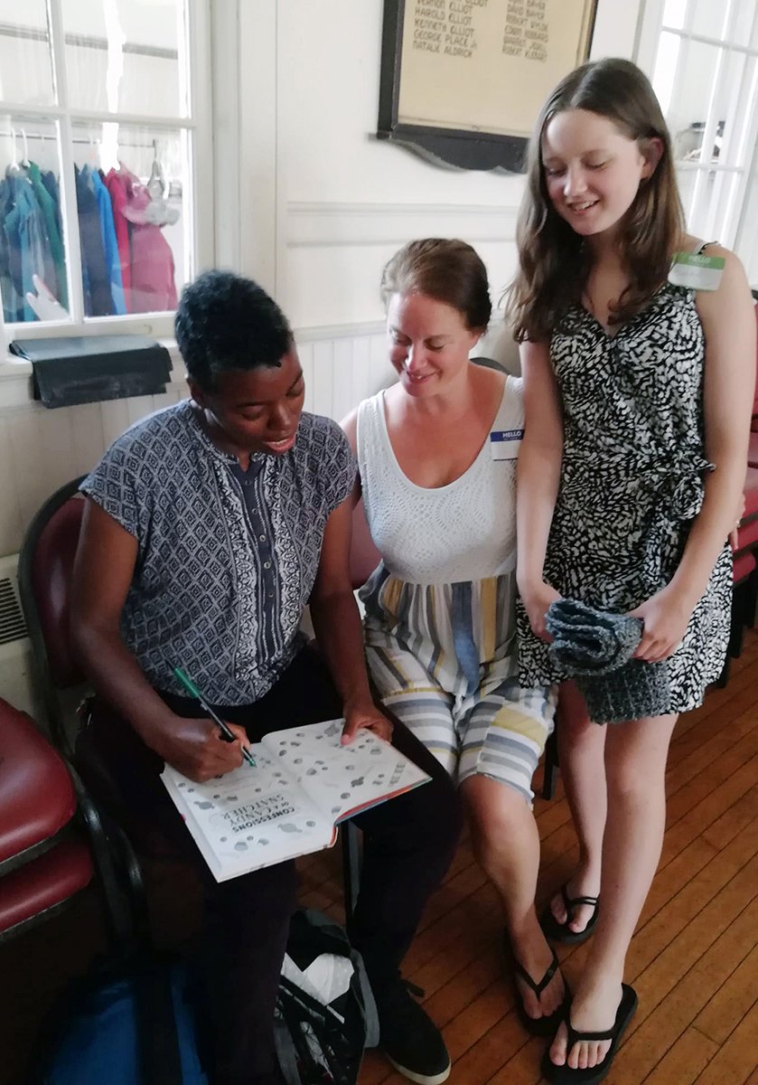 author signs book for two friends, one a teenage girl