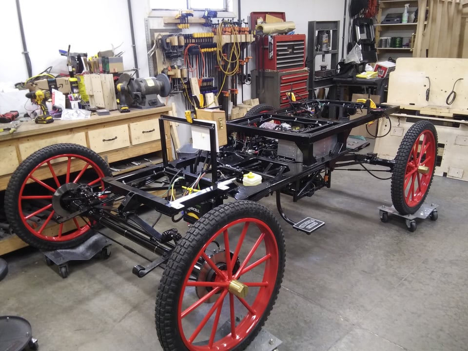 The black metal frame holding the engine, with four, red-spoked wheels attached