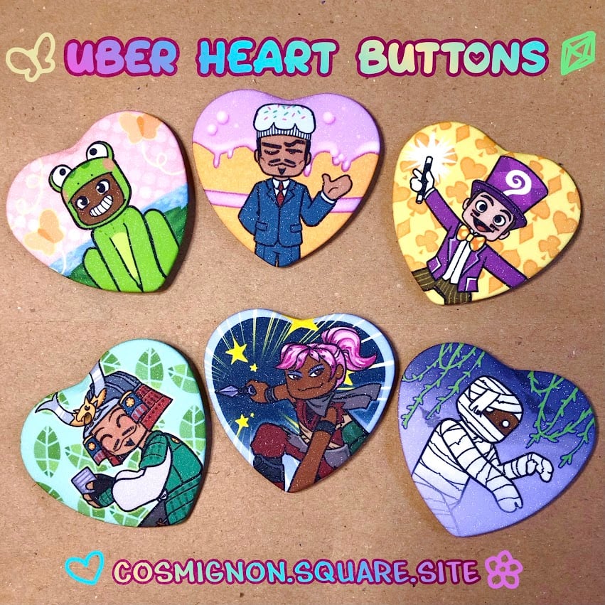 A photo of 6 buttons of 6 blocky characters in different themed costumes. The text reads: "UBER HEART BUTTONS" on the top and "COSMIGNON.SQUARE.SITE" on the bottom.
