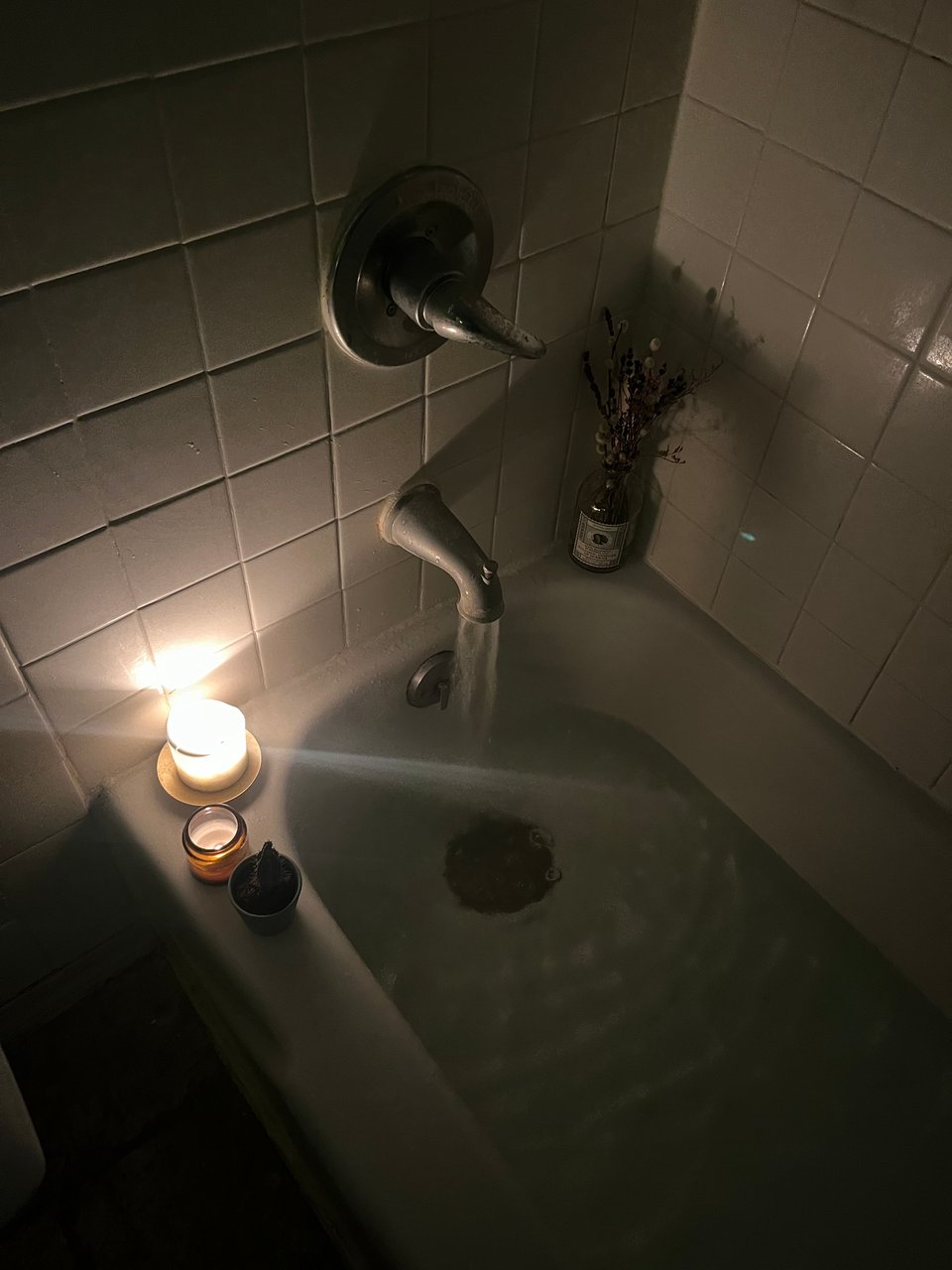 a Beltane bath filling by candlelight, with dried flowers in the corner