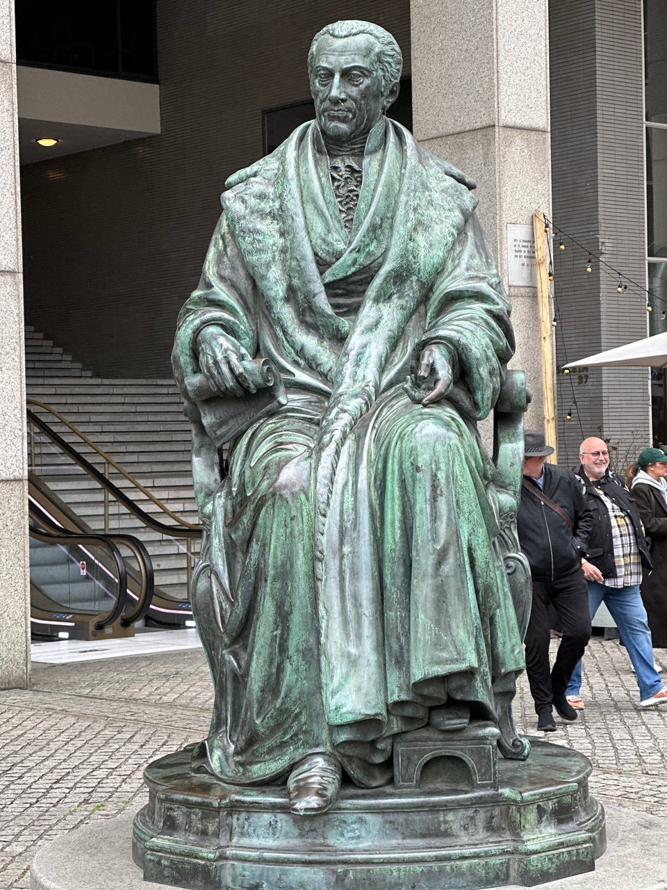 Bronze statue of Gijsbert Karel van Hogendorp, seated, in robes, holding a scroll in his right hand, and left foot up on a little footrest