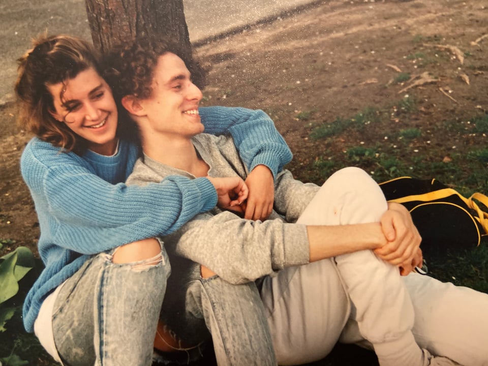 scan of a photo of a white woman and man in their early 20s, sitting by a tree; she has her arms around him and they're both smiling and seem to be happy,, with no idea of what life would be like in the decades ahead