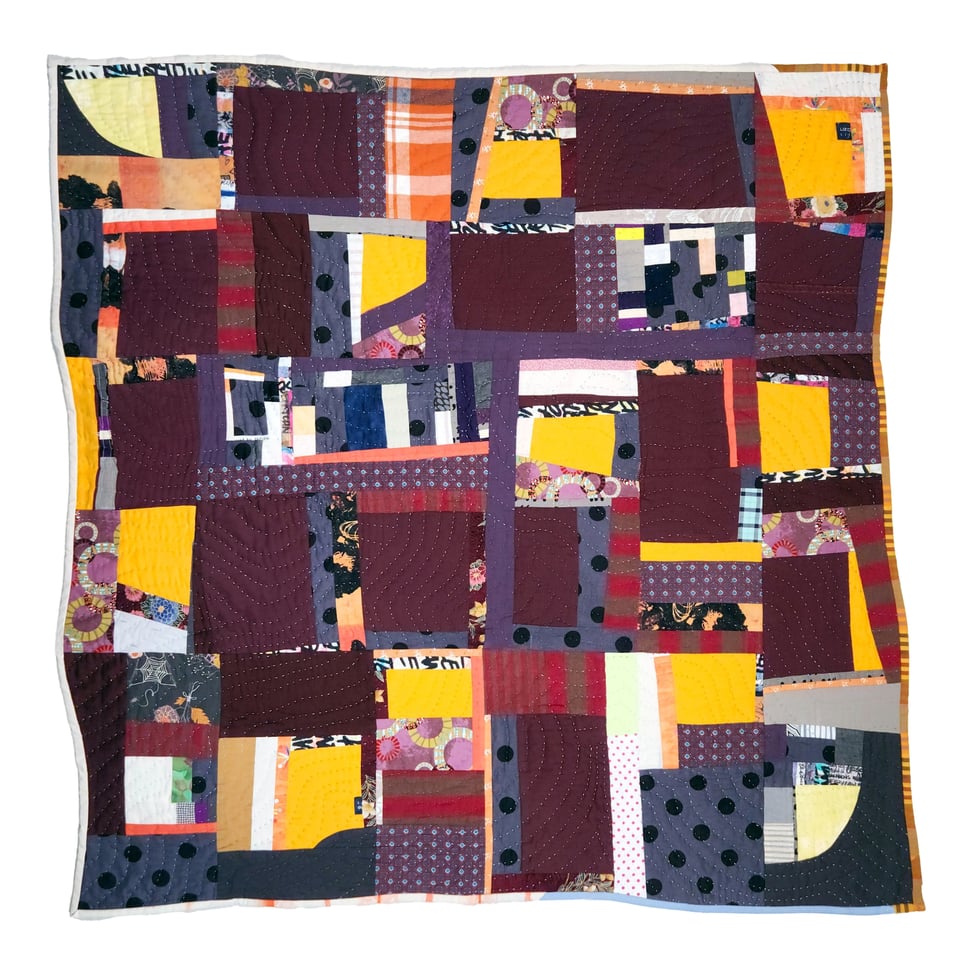 Photo of Spin Me to Sleep, a patchwork quilt by Sarah Atlee. This quilt features squares of dark purple and bright yellow interspersed with strips of white, gray, and orange.