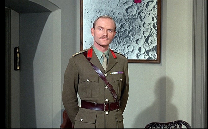 Julian Glover, a white British man, wears a military uniform with nifty red lapels, and a cool belt with cross belt, and looks very fierce with a tiny mustache. He is not to be fucked with.