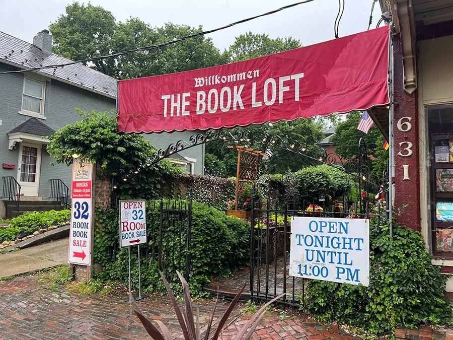 The entrance to the Book Loft. A read banner hangs overhead that says, “Willkommen” and “The Book Loft.” Another sign says “32 Room Book Sale.”