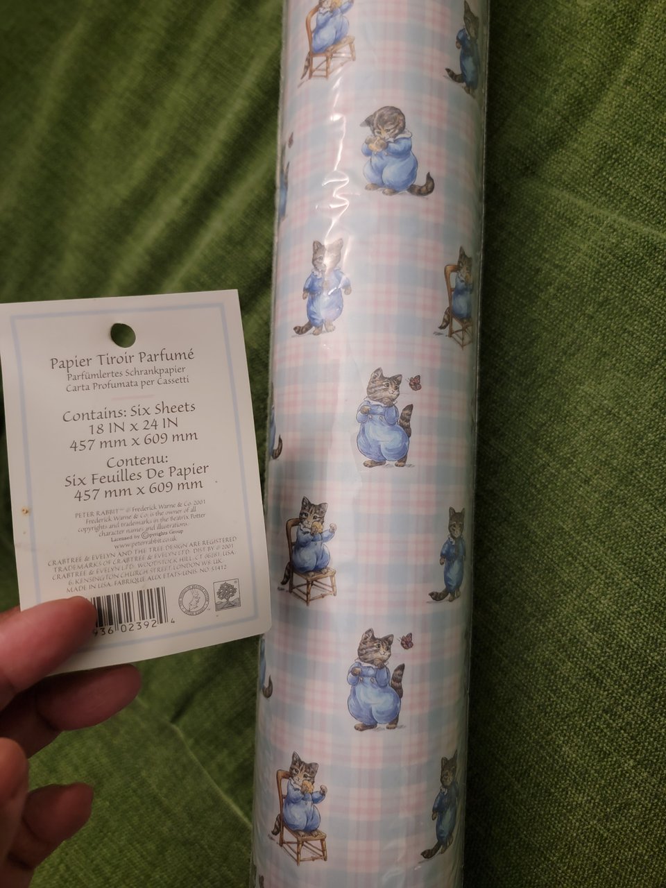 roll of shelf liner with a blue and pink plaid print and chunky kittens in blue outfits