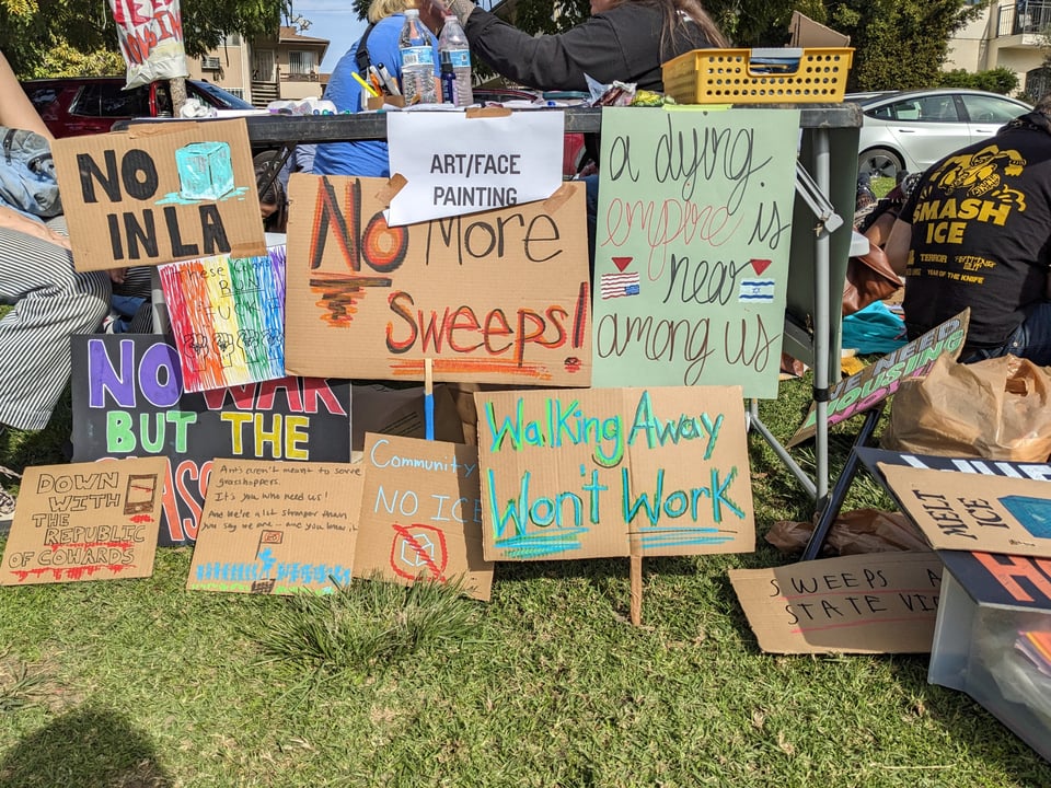 A collection of colorful handpainted signs against ICE and unhoused encampment sweeps