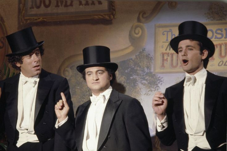 three men in tuxedos singing