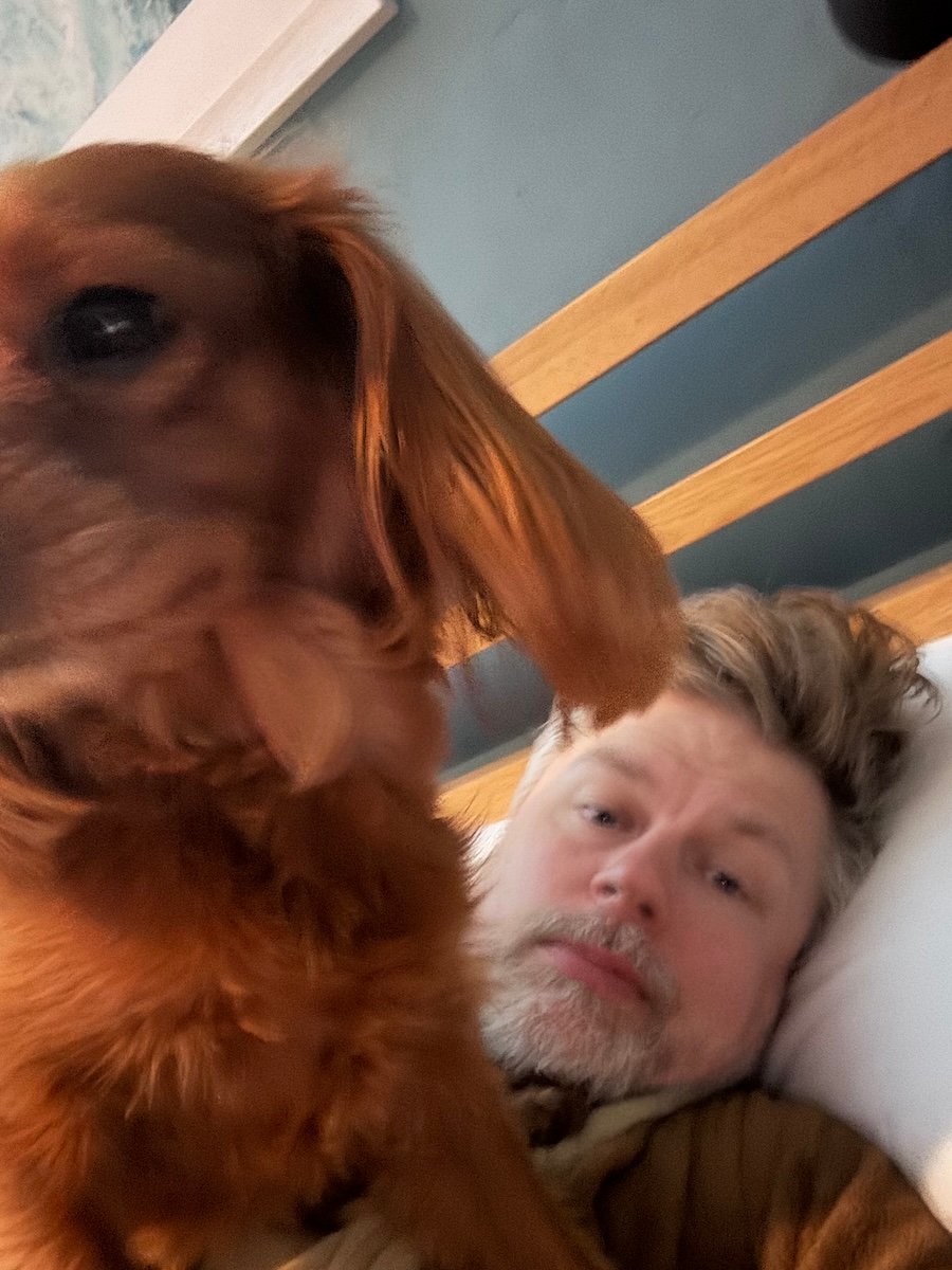 A cute pup sits on a less cute man.