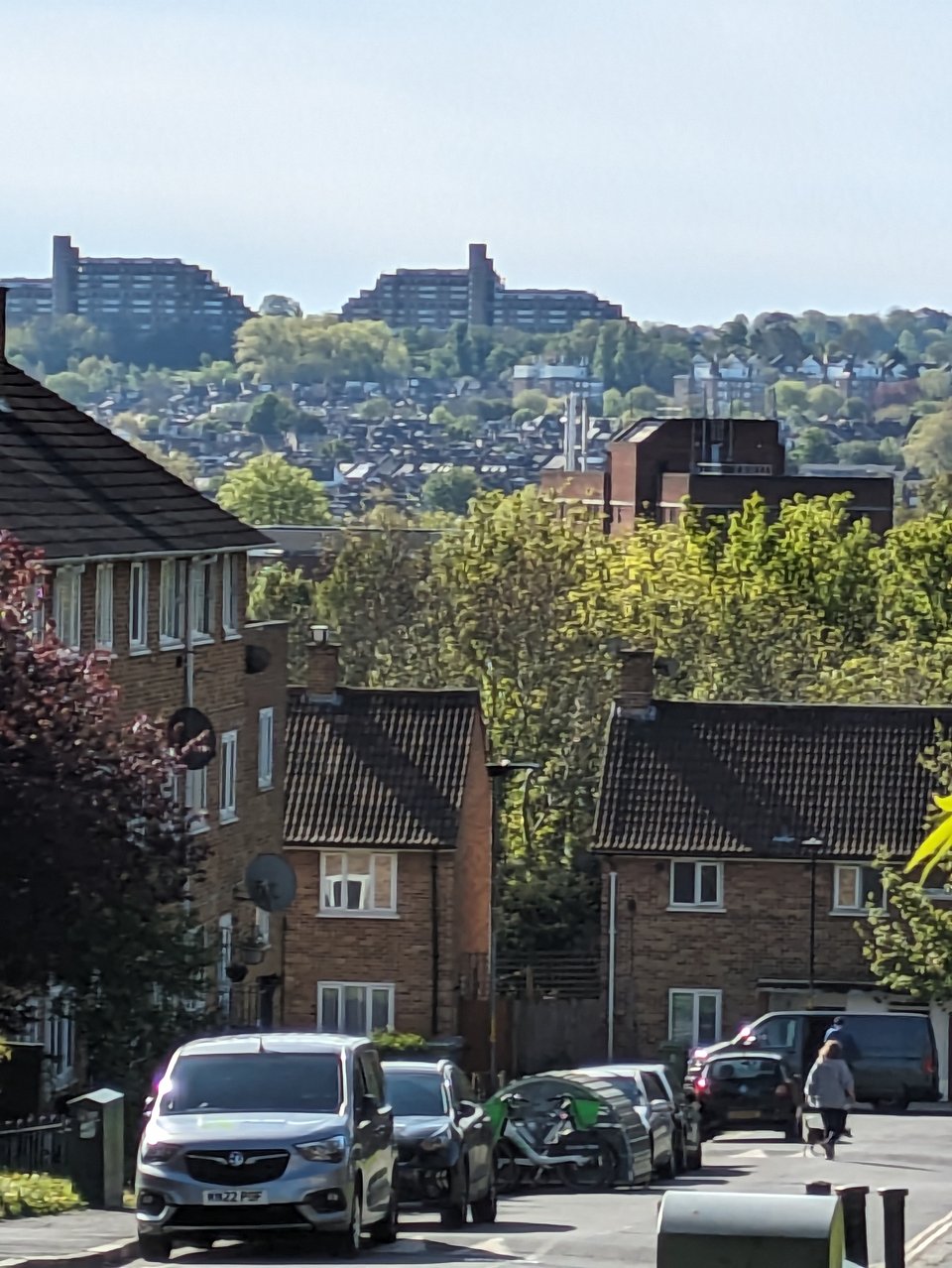 a street on the denmark hill estate with sydenham hill in the background, including a block of flats on the horizon that are shaped like a ship