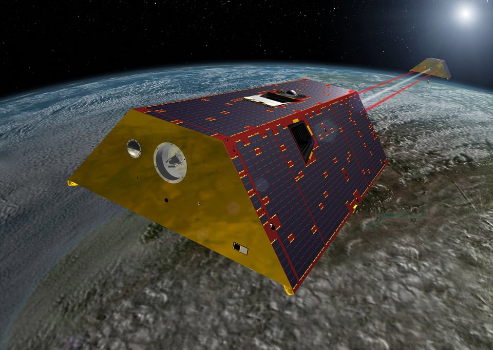A computer-generated image of two satellites shaped like trapezoidal prisms and connected to each other with bright red and white beams. The surface of the Earth is in the background.