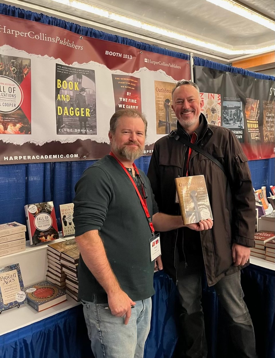 2 handsome gents holding up their wonderful book Oathbreakers, at a display table for HarperCollins