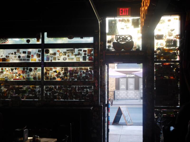 Evening sunlight shining through sticker-bombed bar front windows.