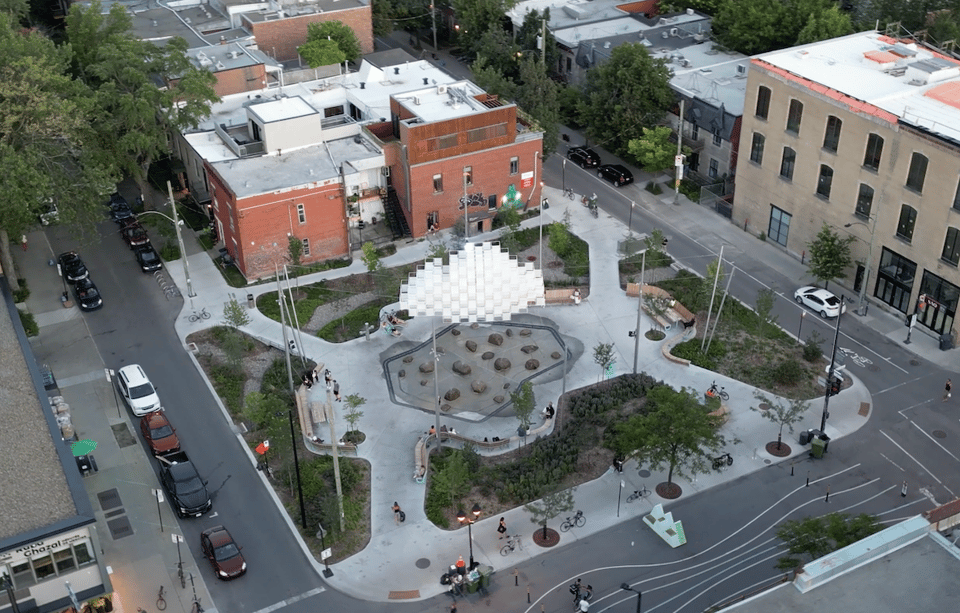 Aerial view of a city park with a cloud-like sculpture suspended above it.
